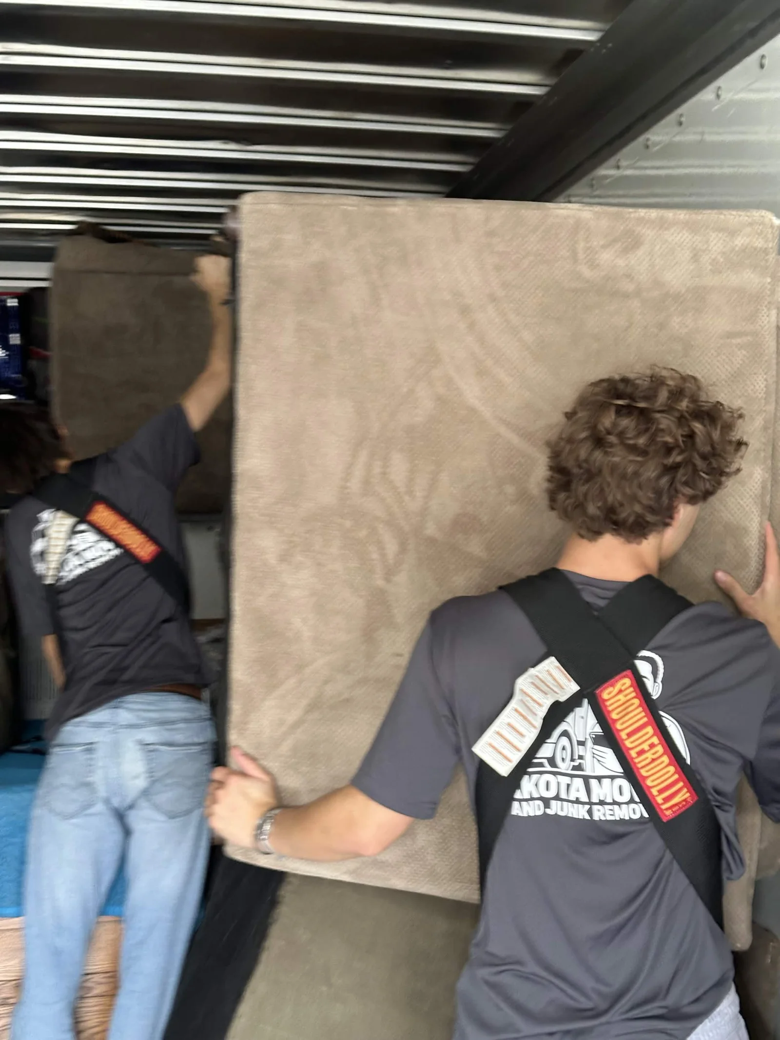 Dakota crew carrying a couch inside a moving truck.