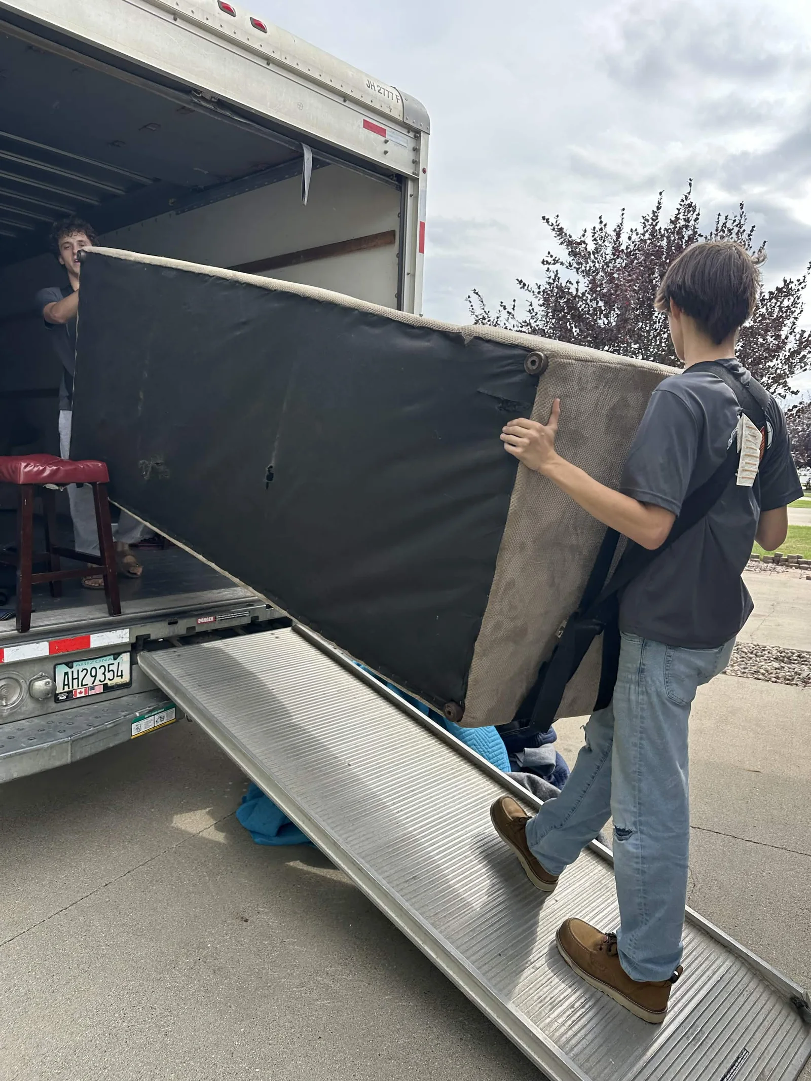 Dakota crew carries a large piece of furniture up a truck ramp